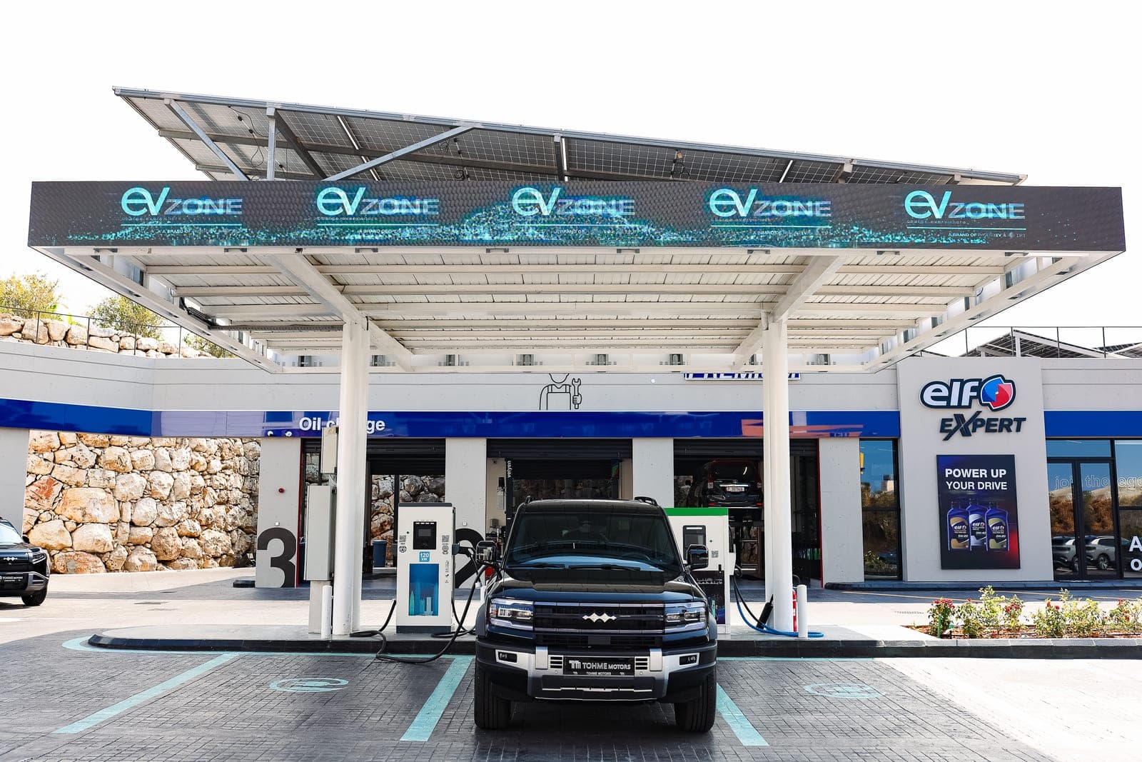 An EVzone charging canopy with vehicles on charge.